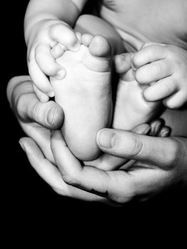 a mother holding a baby's feet with baby's hands touching his feet