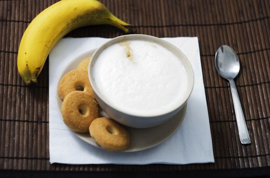 Breakfast with a cup of cappuccino with four biscuits and a banana