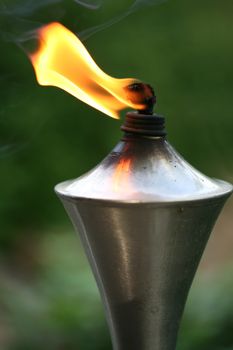 Lit torch with orange flame in garden used as mosquito repellent