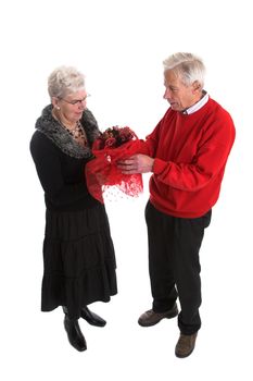 Elderly man giving his wife a bunch of red flowers for valentine