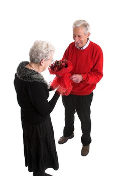 Happy elderly couple; man is giving his wife flowers for valentine