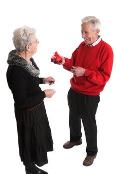 Elderly man giving his wife a box of valentine chocolate with a big laugh