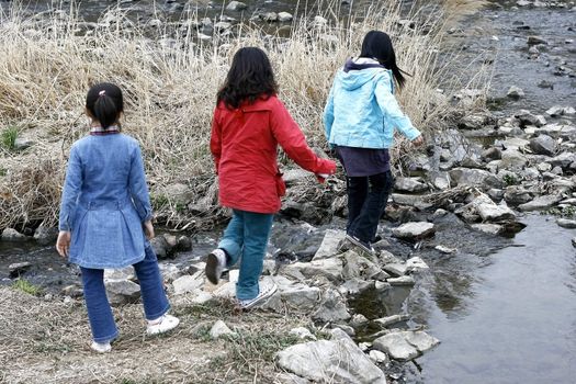 Childrens crossing a small creek in Anyang River Korea