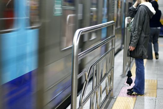 Train station with train approaching and a waiting passenger