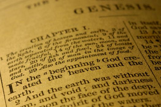 Close-up of the first words of the book of Genesis from a well-used Victorian bible, King James version. Page is yellowed with age and use.