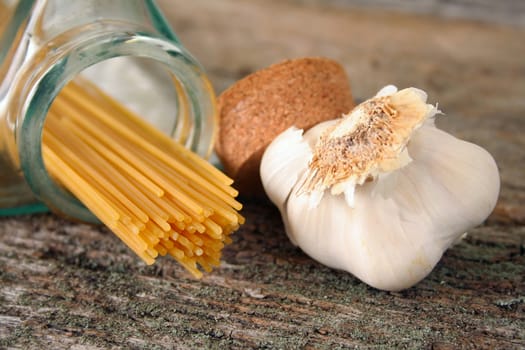 Dried Spaghetti noodles and raw garlic on an old piece of wood.