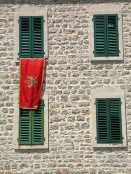 Stone wall with windows, green shutter and Montenegro flag