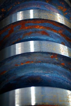 Close up image of a rusted steel shaft with blue and red weathered colors