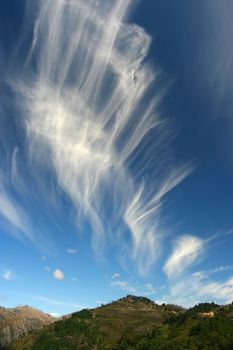 Photo of beautiful swirly clouds over hills.