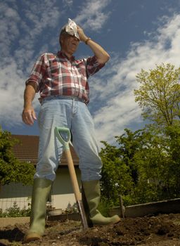 A man, mopping his brow after a bout of heavy digging in the garden