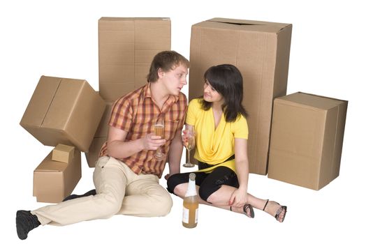 Girl and the guy drink champagne near boxes on a floor