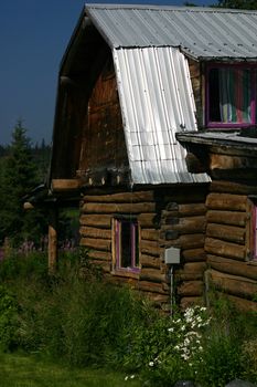 Rustic environmentally friendly log cabin nestled in the pristine forests of southern Alaska exemplifies the rugged individualism of those who settle there.