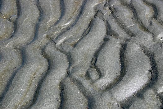 Abstract shapes and textures formed by ripples of water and gentle waves on the beach.