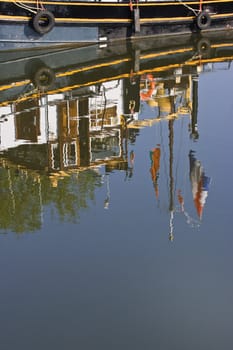 Reflection of part of ship with flags on summer morning