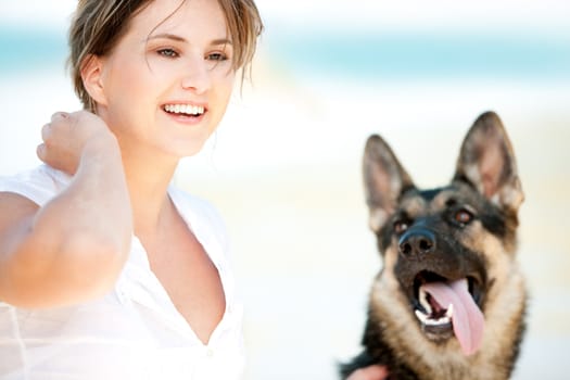 Young woman enjoying a sunny summer day on a beach with her dog