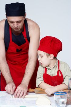 The father with the son work up dough. A transfer of experience . 