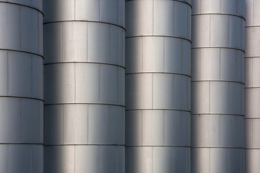 a row of metal round grain storage bins with rivets - industrial background and texture