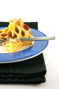 Raspberry and custard danish on a blue and white plate with a fork and black napkin on a white background