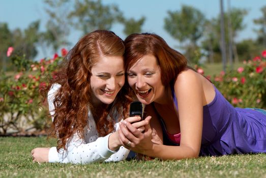 Two girlfriends in park with a mobile phone