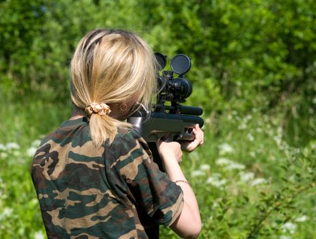 The girl aims from a gun with an optical sight.