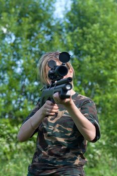 The girl shoots from an air rifle with an optical sight.