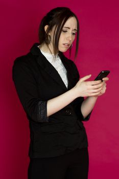 Young business woman reading message on her smart phone with disturb expression against pink background