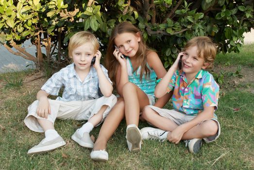 Group of children sitting in park with mobile phones