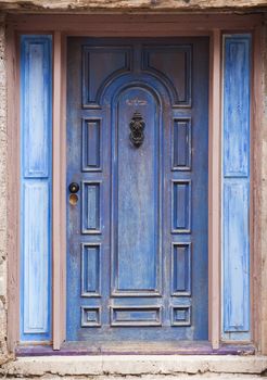 Old peeling blue door with metal knocker