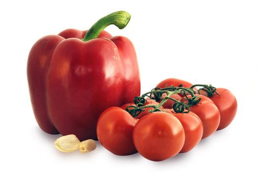 Delicious and nutritious vegetables: ripe tomatoes on the vine with a red pepper and cloves of garlic.