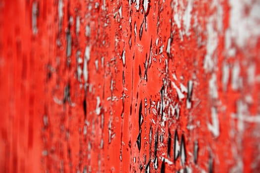 Peeling bright red paint on old door shot at an angle to get that very shallow DOF effect,focus in middle tier.