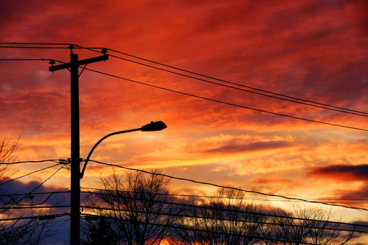 Sun setting over the electricity post and cables of a small town.