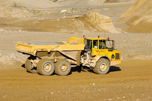 A yellow dump truck is driving in a mine