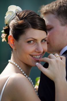 Portrait of newlywed smiling bride leaning on grooms shoulder.
