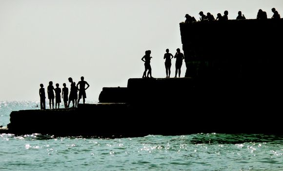 Silhouetted people on a sea defence on the Brighton coast.