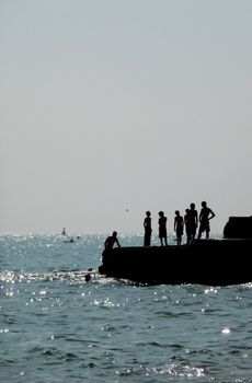 Silhouetted people on a sea defence on the Brighton coast.