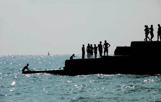 Silhouetted people on a sea defence on the Brighton coast.