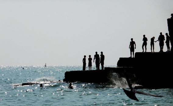 Silhouetted people on a sea defence on the Brighton coast.