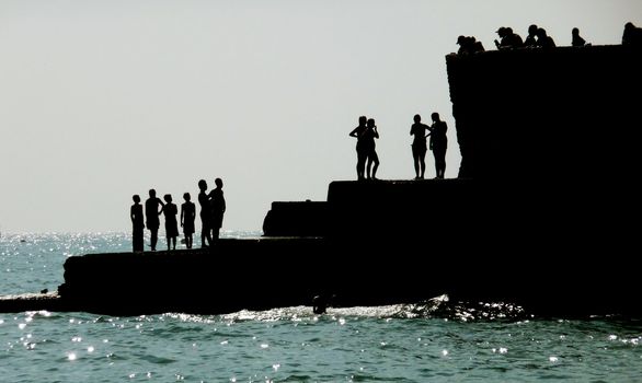 Silhouetted people on a sea defence on the Brighton coast.