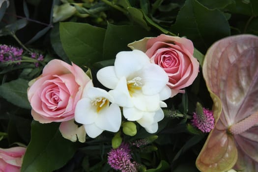 A floral arrangement made of soft pink roses and white freesias