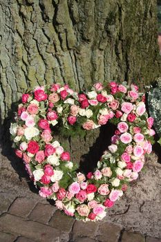 A sympathy flower arrangement, heart shaped and made of pink roses