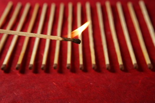 Light wooden matches arrangement in a row over red background