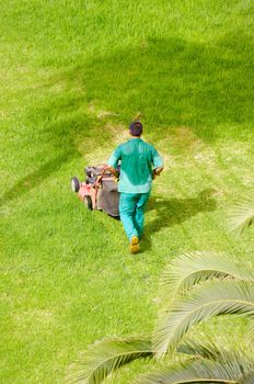 Man is mowing grass on a hot summer day.