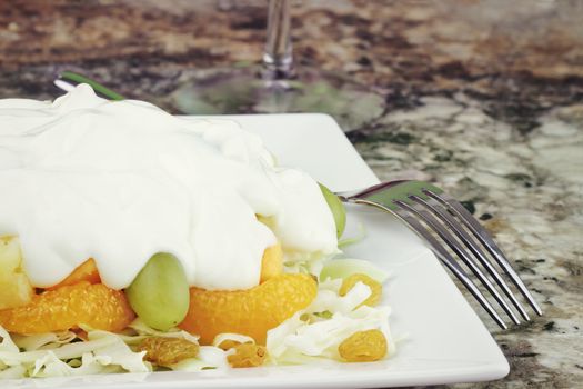 Fruit & Edam salad. A bed of shredded cabbage layered with grapes, mandarin oranges, golden raisins, pineapples, green grapes and edam cheese topped with a creamy sweet sauce of yogurt and sour cream.  
