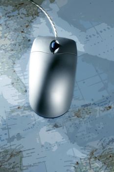 Computer silver wired mouse over blue blurred map