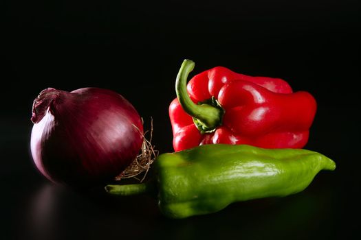 Vegetables still with onion and pepper over black background