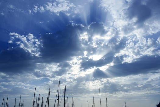 Cloudy sunset beam sky with marina sailboat masts on bottom