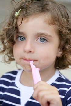 Little blue eyes girl eating sweet candy with dirty face