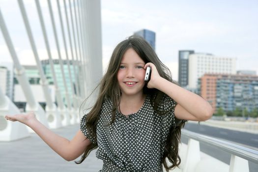 Adorable teenager little girl talking phone downtown in city bridge