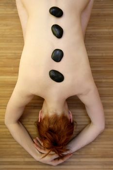 Beautiful woman relax with black stones on her back