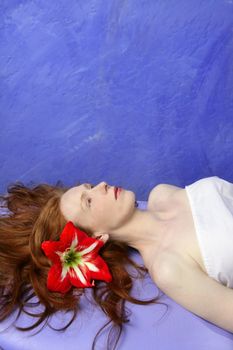 Beautiful redhead woman in a vivid massage blue board, orange flower